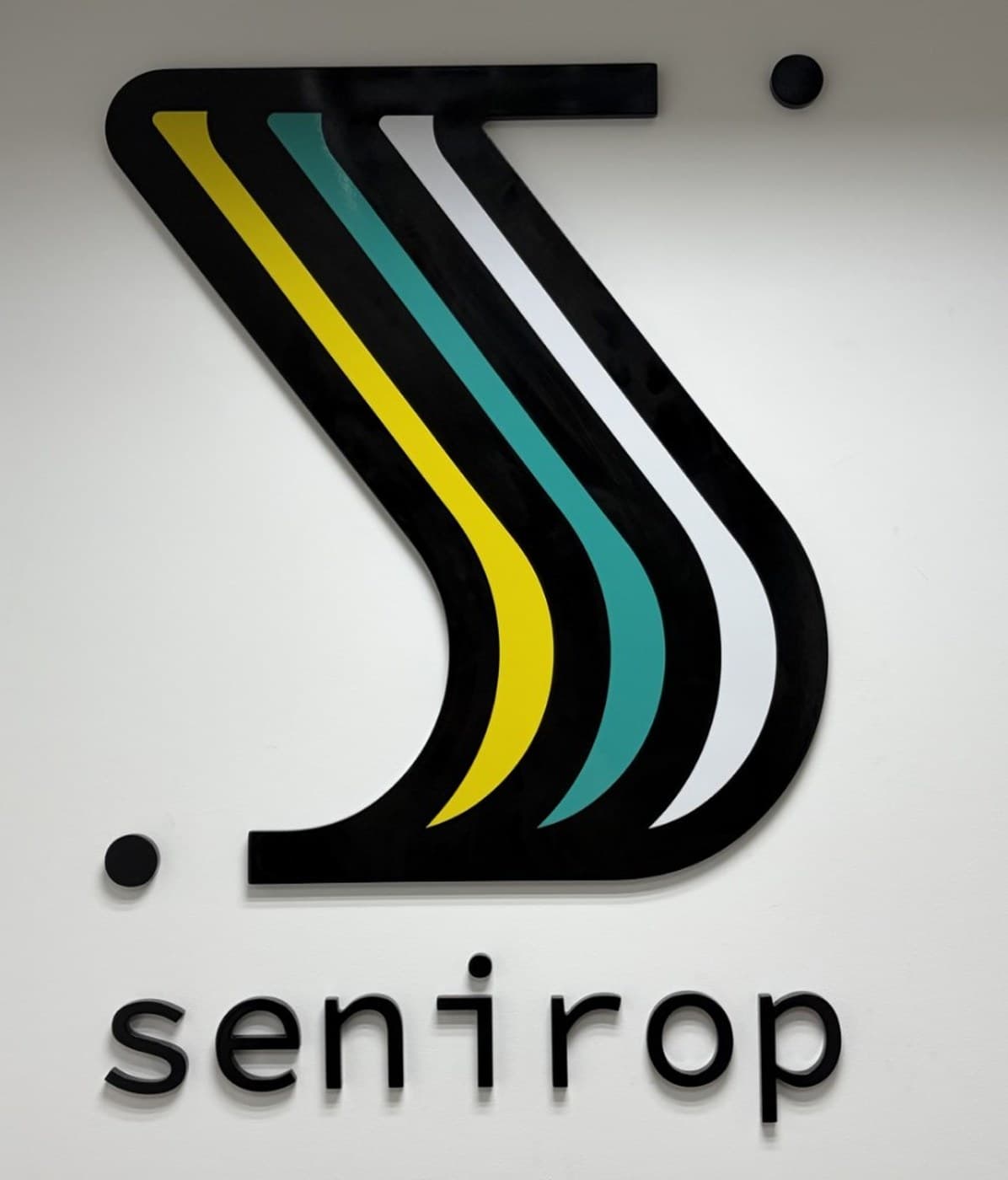 The Senirop logo mark and wordmark mounted on the wall of the company's Quito, Ecuador office